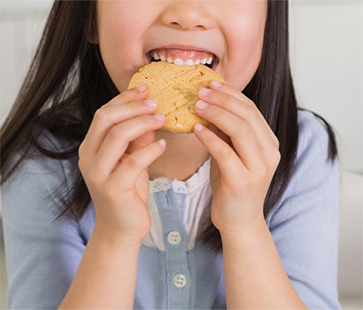 Smiling child eating a cookie—flavour that brings joy.