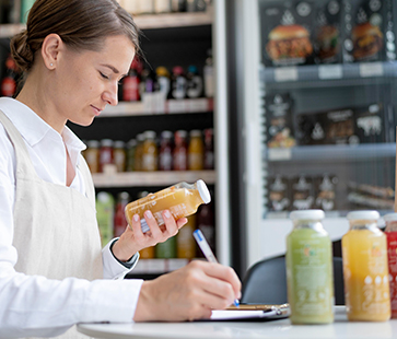 Woman reading juice label in store—transparency you can trust.